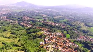 Şehrin kıyısındaki yoğun nüfuslu yerleşim yerinin sinematik hiper hatası. Bandung bölgesindeki yeşil pirinç tarlalarının manzarası, Endonezya. Tarım endüstrisi. Panoramik Peyzaj. 4k Görüntü 