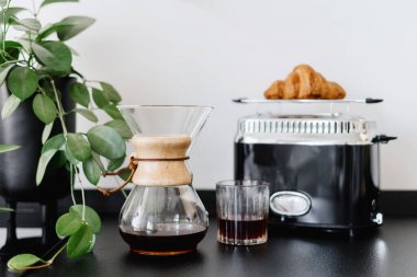 Alternatif kahve demleme yöntemi, sıcak kafein içeceği ile cam chemex ve mutfakta kızarmış ekmek kızartma makinesinde taze kruvasan.