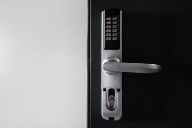 Door access control. Temporary digital code for opening the room. Close up view of self check in at hotel or apartment. Metal handle with keypad on smart security system against white copy space wall clipart