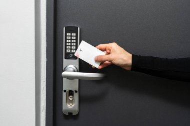 Modern güvenlik sistemiyle kendini kontrol etme kavramları. Otel odasındaki kapıyı açmak için plastik kart kullanan bir kadın görüntüsü. Anahtarsız kilit, kablosuz teknoloji ve giriş için geçici kodlar