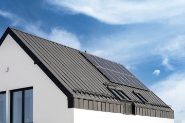 Metal galvanize kaplama üzerinde güneş fotovoltaik panelleri olan bir bina çatısı. Çatıda yenilenebilir enerji elementleri olan özel bir ev. Reklam kavramları