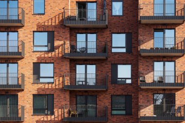 İnşaat sektörüne yatırım kavramı. Metal pencere çerçeveli ve açık balkonlu yeni ve modern tuğla evin ön yüzü ya da önü. Konut kredisi kavramı