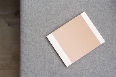 İç mekanda minimalist stil, tekstil döşemeli kanepe manzarası ve oturma odasında maketi olan kapalı dergi, okuma ve çalışma konsepti.