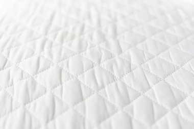 angled shot of new orthopedic hypoallergenic foam mattress with protection surface on bed in bedroom, texture of topper, background