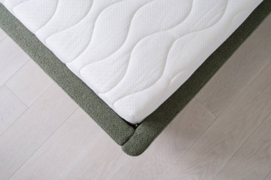 Evdeki modern yatakta beyaz pamuk kaplı yeni ortopedik yatak, rahat uyku konsepti.