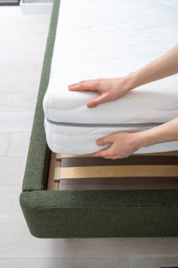 Kırpılmış kadın eli. Mobilya mağazasında pamuk kılıfında rahat bir yatak seçiyor. Sağlıklı uyku konsepti.