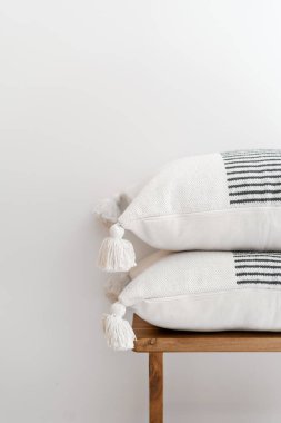 Pamuk tekstil kaplamalı yastıkların, tahta püsküllü bankların beyaz arka planda fotokopi alanı, boho tarzı, yatak odasının iç kısmında detay