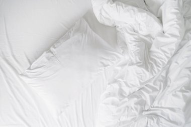 Pamuk örtülü yumuşak yastığın üst görüntüsü yatak odasındaki rahat yatağın yorganı kırışık yüzey, dağınık yatak örtüsü sabah uyandıktan sonra yapılmamış yatak.