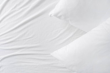 Pamuktaki yumuşak yastıkların üst görüntüsü rahat yastık kılıfı üzerinde otel odasında yatak örtüsü, buruşuk yüzey, fotokopi alanı olan arka plan.