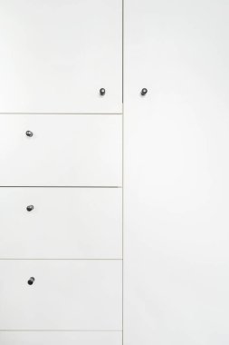 Kapalı kapılı ahşap beyaz gardırop ve siyah metal saplı çekmeceler dairede yatak çarşaflarının saklanması mobilya mağazasındaki modern giysi dolabının ayrıntıları.