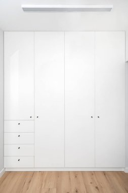 Kapalı kapılı ahşap beyaz gardırop, dairede siyah metal saplı çekmeceler, İskandinav iç çamaşırlı modern giysi dolabı.