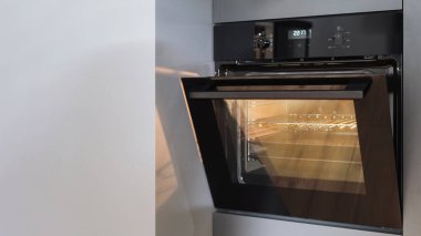 Kapısı açık elektrikli fırının kapağı ve mutfağı aydınlatacak modern ev aletleri, evde yemek pişirme.
