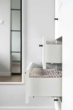 Açık çekmecelerde temiz banyo havluları ya da temiz çarşaflar içinde modern beyaz gardıropta ayna ve aydınlık iç mekanlı oda, organize uzay konsepti