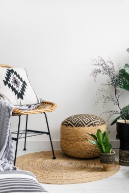 Dairesinde detaylar, boho iç döşeme, yumuşak ekose ve yastıklı rattan sandalye desenli kaplama, hasır puf ve yerde yuvarlak halı üzerinde saksı bitkileri