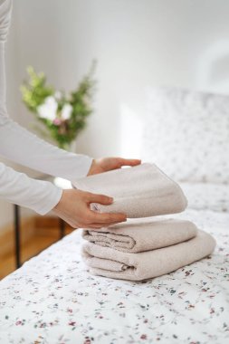 Kadının dikey görüntüsü otel odasındaki yatağın üzerine temiz ve beyaz havlular koydu. Yatak odasında yeni yıkanmış bir kadın var. Ev işleri ve ev işleri