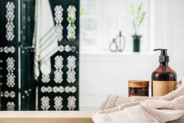 Bulanık banyo içlerine karşı kozmetik ürünlerle dolu raflar. Duş jeli şeker şişesinde, cam kavanoz ahşap kapaklı ve masa üzerinde yumuşak havlu. Hijyen, bakım ve kişisel bakım konsepti