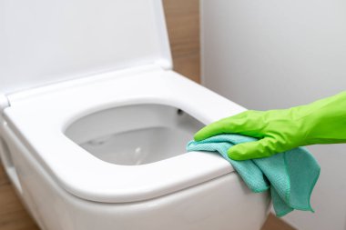 Modern banyoda mavi bir bez klozet temizleme eldiveni ve yeşil kauçuk koruyucu eldiveni kapat. Banyo ve tuvalet hijyeni. Yıkama ve klozet kapağını dezenfekte etme