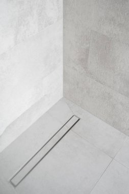 Lüks banyodaki modern muhafazanın fayanslı zemininde doğrusal duş gideri, su yok etme sistemi, tavan arası tuvaletinin iç kısmı, minimalist stil.