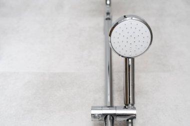 Modern banyo içerisindeki detaylar. Krom duş başlığının yakın görüntüsü oteldeki ya da apartmandaki fotokopi alanı olan fayanslı duvar zeminine karşı.
