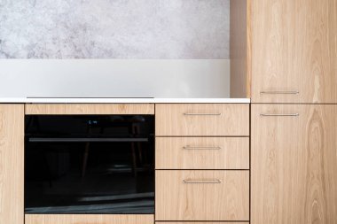 Ahşap cepheli mutfak modülü ve mikrodalga modu olan yeni siyah entegre fırın. Modern apartmanda ev aletleri kavramları