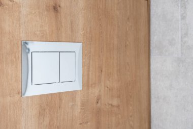 Modern gizli sarnıç ve şık banyodaki ahşap mobilya arka planında su sifonu kontrolü için değiştirme. Otel odasındaki tuvaletin duvarındaki tesisat ayrıntıları.