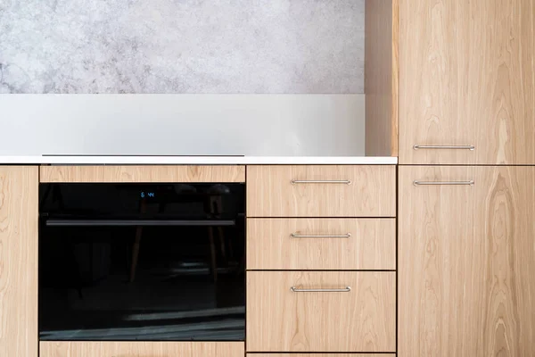 带有木制立面的厨房模块前视图和带有微波模式的新型黑色集成烤箱 现代公寓中家用电器的概念 — 图库照片