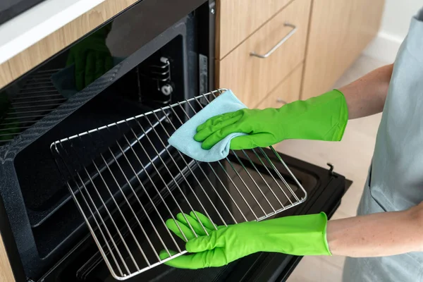 戴橡胶手套的妇女高角镜清洁烤箱内的烤栅 女人们用桌布擦拭厨房里的家用电器 家务劳动和清洁服务的概念 — 图库照片