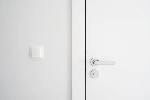 金属ハンドルとロック付きの近代的な閉じたドアの近くのビュー 入り口近くにライトスイッチ付きの白い壁 プライバシーと安全の概念 スペースのコピー — ストック写真