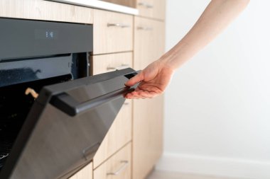 Elektrikli fırında cam kapıyı açan kadın görüntüsü. Ev hanımı boş mikrodalga fırın kullanıyor, evde yemek pişiriyor. Ev aletleri, fırın ekipmanı konseptiyle yapılmış mutfak.