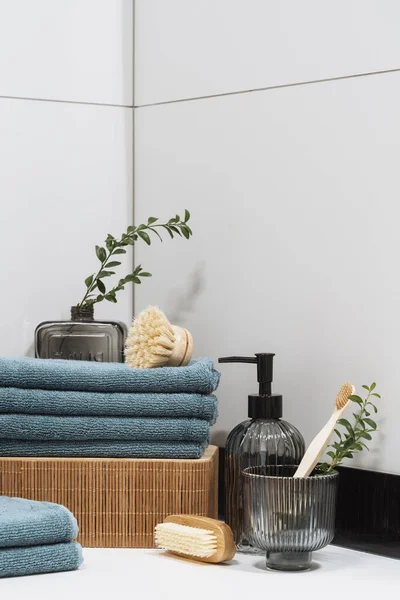 stock image closeup of clean towels neatly folded, wooden toothbrush in glass, dispenser bottle and bamboo massage brush for beauty rituals, concept of body care and dental care