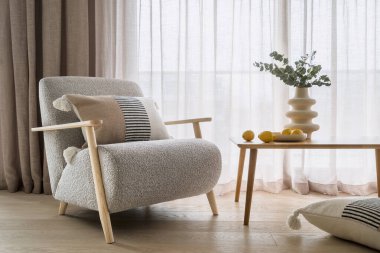 Ev dekorasyonu ve mobilya konseptleri. Tahta masanın yanında bohem tarzında minderleri ve beyaz geometrik vazoda çiçekleri olan zarif koltuklar. Daire içinde pahalı tasarım nesneleri