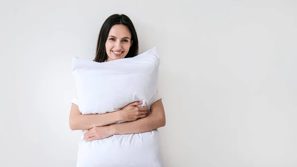 カメラを見ている若い笑顔の女性のスタジオ撮影は メモリ泡と枕を受け入れる 白いコピースペースの背景にソフトクッションを持つ女性 幸せな朝の広告コンセプト — ストック写真