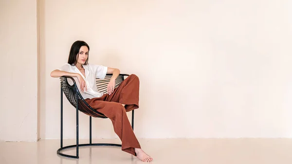 stock image Advertising concept collection of pajamas, sleepwear and nightwear with natural cotton fabric. Woman posing for catalog or look book. Fashion model in casual wear sitting in metal armchair at studio