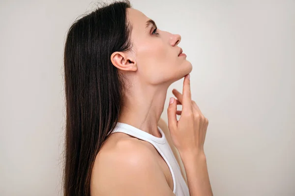 Aesthetic medicine, dermatology concepts. Profile view of woman with perfect face contour touching her neck. Cosmetology clinic with procedure for skincare, rejuvenation, wellness and spa treatment