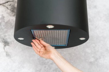 Kadın temizlik ya da hizmet için yemek pişirme kabuğundan filtreyi çıkarıyor. Mutfak vantilatöründeki kirli elementleri değiştirme işlemi. Dairede yemek pişirirken hava arındırma için modern bir alet.