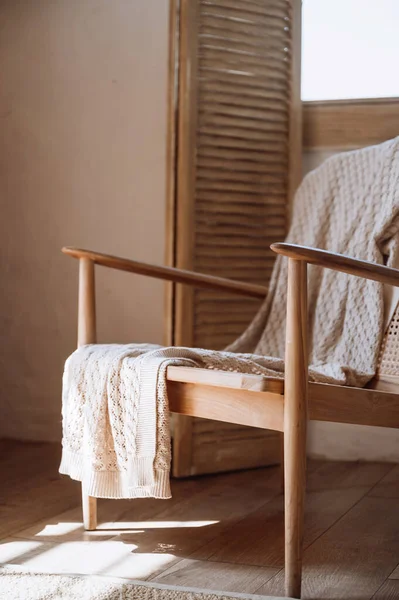 stock image Close up view of wooden armchair with cotton knitted plaid on home furniture. Chair in cozy living room. House with scandinavian design. Restoration concepts