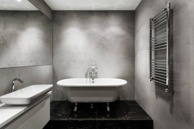 Gri renkte banyo, minimalist tarzda banyo, banyo, lavabo dolabının altındaki lavabo, duvarda ısıtmalı radyatör ve yerde fayans.