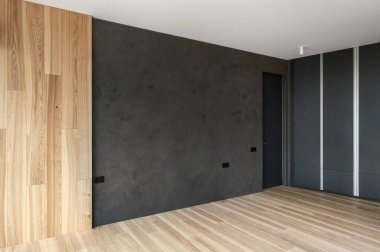 Konut binasında yenilenmiş bir dairede modern iç mekanı olan bir oda. Çatı katı tarzında gri beton duvar ve boş yaşam alanında ahşap kaplama zemin