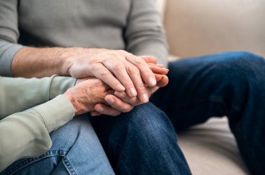 Oturan ve el ele tutuşan olgun çiftin yakın görüntüsü. Kocası bunalımda olan karısına destek oluyor. Evlilikte empati ve anlayış. Aşk ve güven kavramı