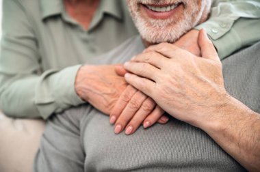 Üst düzey çiftlerin ellerine odaklan. Kadın kocasına sarılıyor. Sevgisini, şefkatini ve mutluluğunu ifade ediyor. Uzun evlilik kavramı ve samimi duygular.