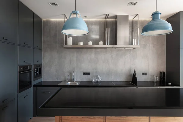 厨房的前视图 黑色的空桌和现代的内饰相对照 金属沉淀池和灰色背景的盖子 橱柜上的内置设备 复制空间 — 图库照片