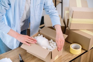 Müşteri için paket teslimatı hazırlayan kadın görüntüsü. Girişimciler nakliye için kırılgan malları düzenliyorlar. Ecommerce için küçük bir depo. Sevkiyat hizmeti reklamı, sevkiyat işi