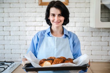 Modern mutfakta, önlüklü, ev yapımı fırınlı mutlu kadın portresi. Aperatif kokulu gevrek glütensiz un ve tohumsuz çörek..