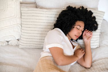 Pijama giymiş Afro-Amerikan bir kadının gece rahat yatak odasında yastıkların üzerinde kapalı gözlerle uyuduğu en iyi görüntü. Derin bir rahatlama. sağlıklı uyku kavramı