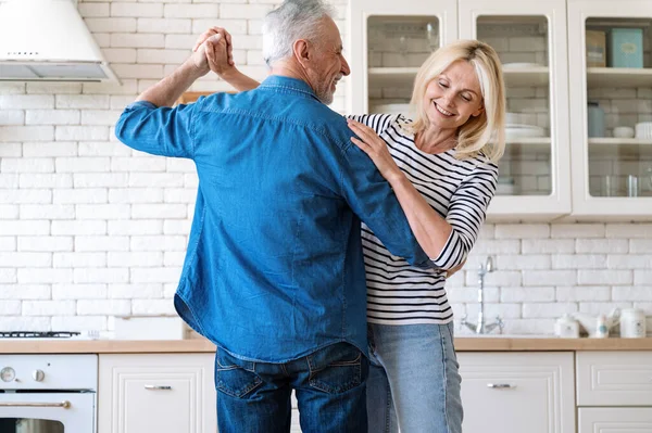 Love in reltionship. Concept of celebration anniversary or family holiday. Happy mid age married couple dancing together at home. Husband and wife listening music and enjoying moment