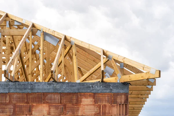 House development. Building under construction. Roof installation with wooden boards on rooftop. Timber frame on attic with metal joints on top against copy space sky on background