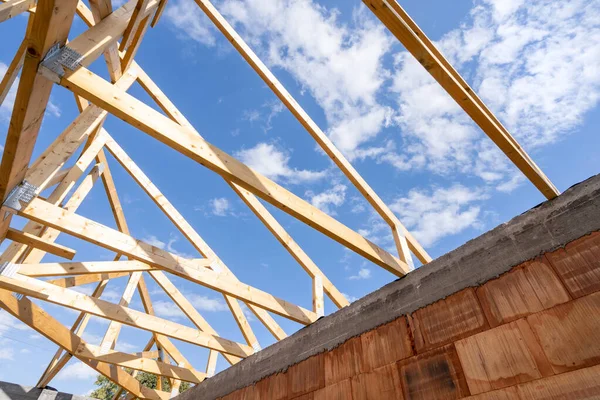 Low angle shot of element of wooden roof with support joist, boards and timber planks against blue sky on background. Construction site, architecture industry. Concept of remodeling, renovation house