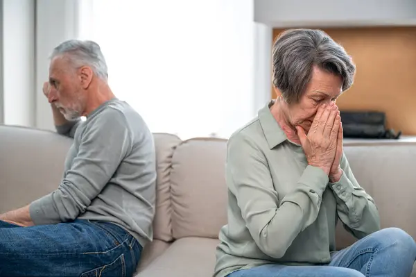 disappointed mature couple. sad middle aged woman sitting turned away from her husband, thinking about divorce. elderly man hurt feelings her wife, problems in relationship.