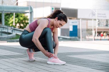 Koşudan sonra ayak bileği burkulmuş genç bir kadın, dışarıda antrenman yapıyor. Kas krampı. Spor giyim sektöründe bir kadın bacağından yaralı, eklem yerindeki acı hissi...