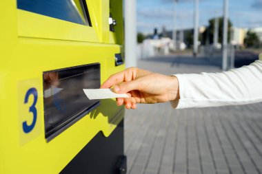 Şehirdeki traport istasyonunda kadınların elindeki kağıttan bilete odaklan. Modern otomatik terminal makinesinden belge alınıyor. Boşluğu kopyala